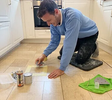 Technician kneeling to repair a kitchen floor