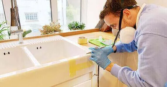 Technician working on a white ceramic kitchen sink