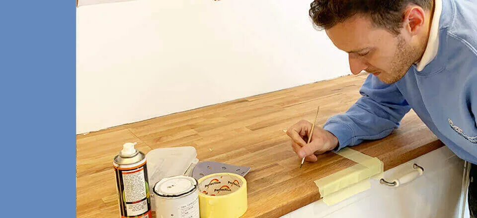 Close-up of a technician filling damage on a solid wood worktop